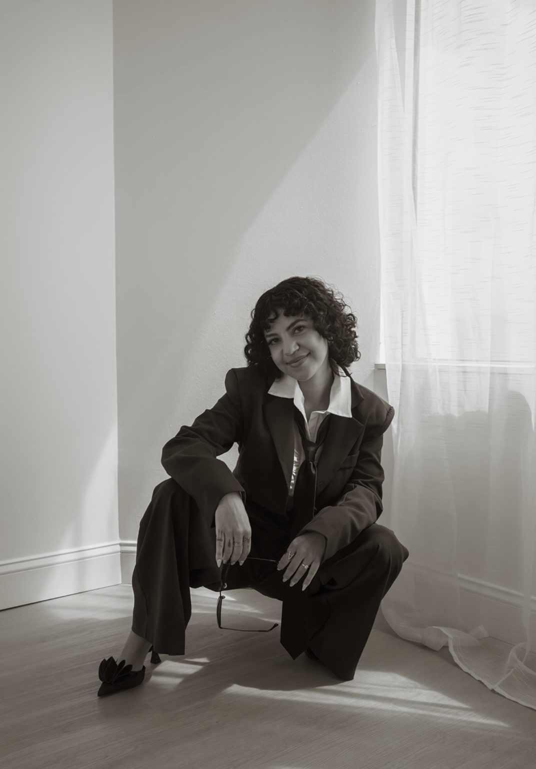 Annie crouching by a window in a suit