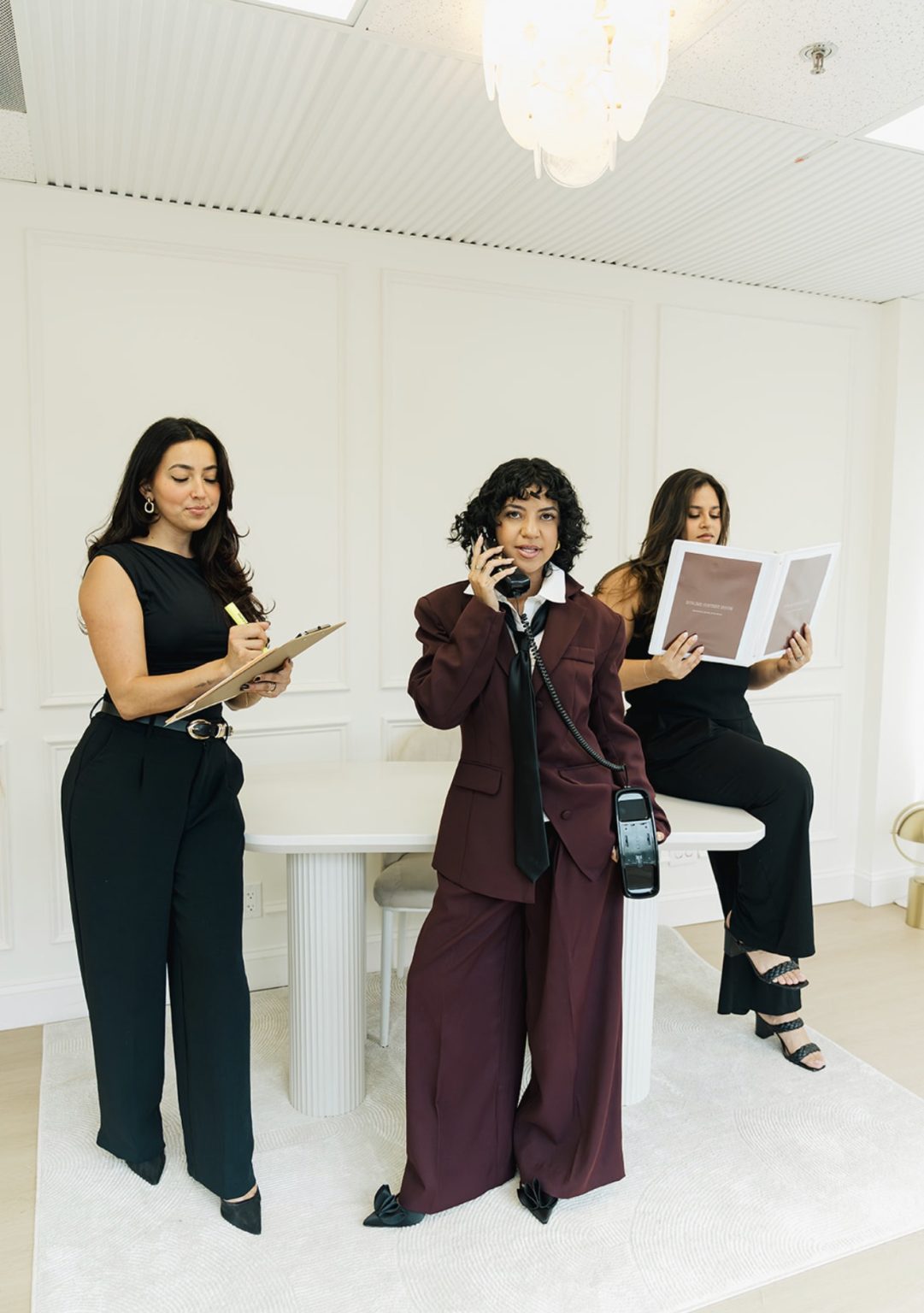 Annie on a rotary phone with her two associates reviewing notes