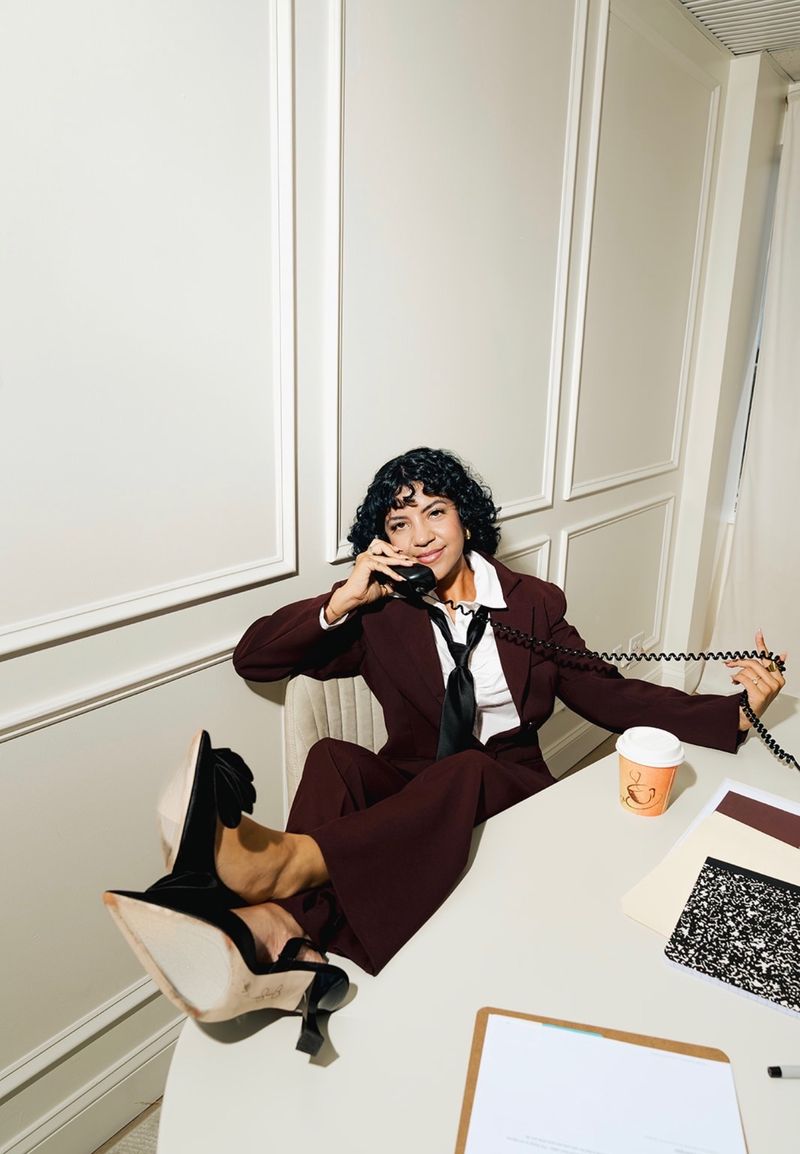 Annie on the phone at her desk in a burgundy suit